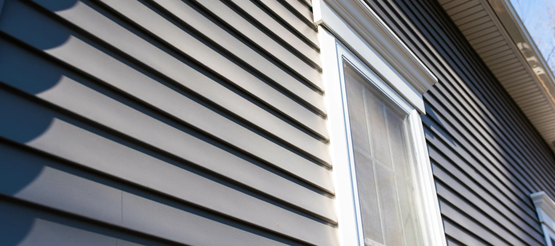 Close-up of dark gray vinyl siding with a window