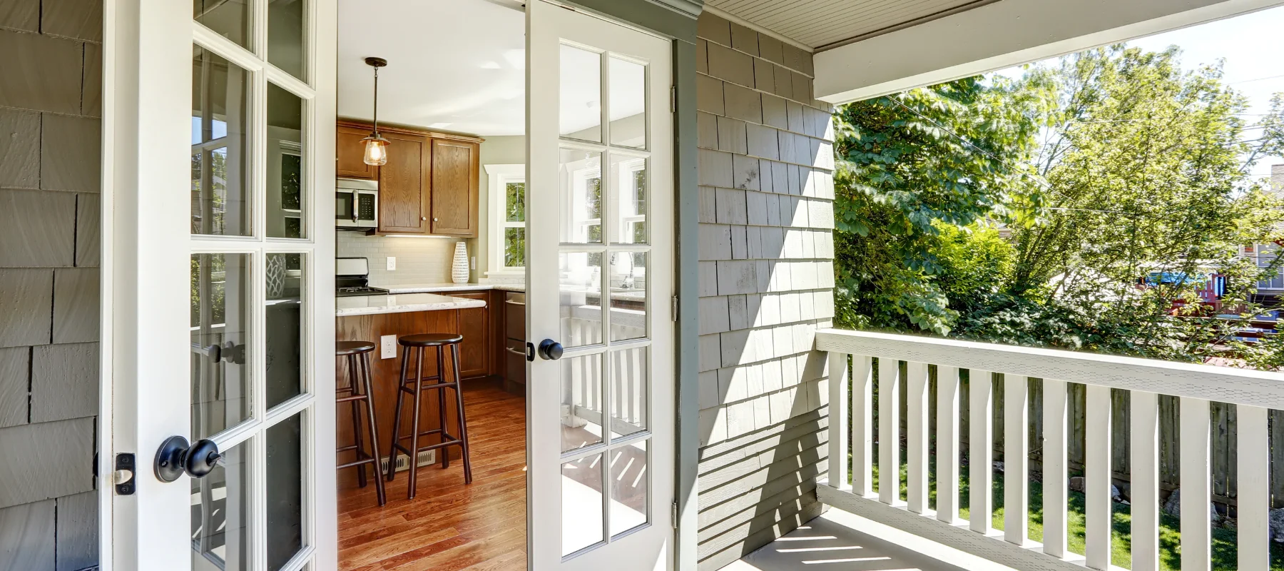 A view of a kitchen from an outdoor balcony, framed by elegant French doors