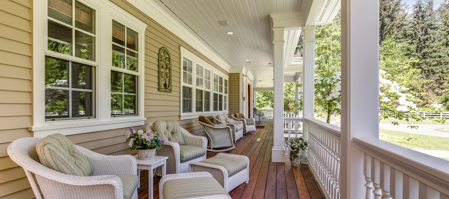 charming wraparound porch with white wicker furniture and lush greenery