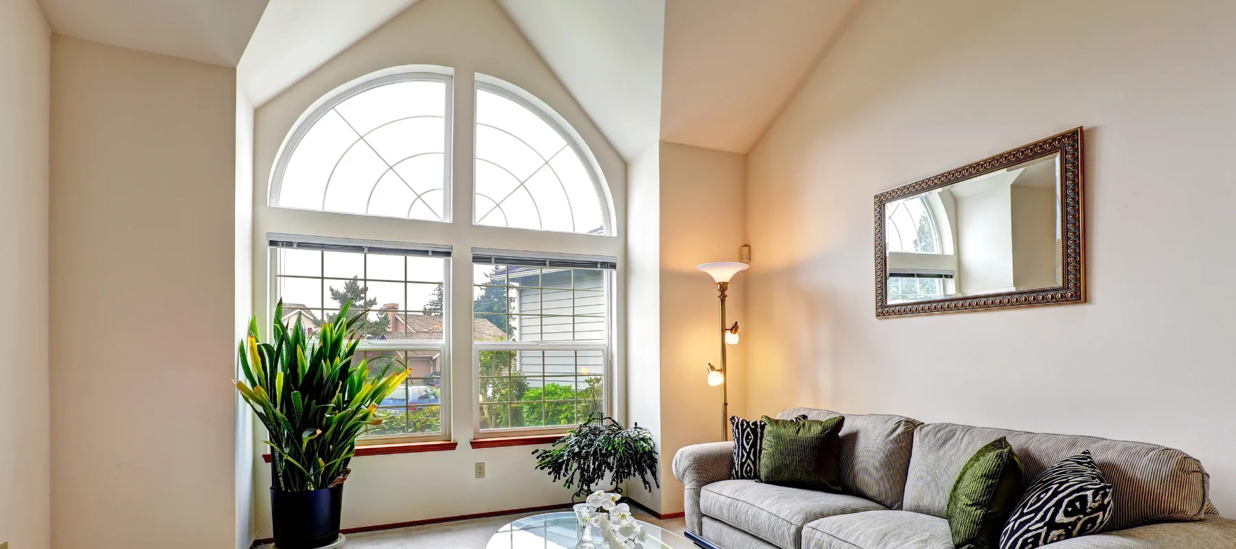 A bright living room with a large arched window letting in natural light