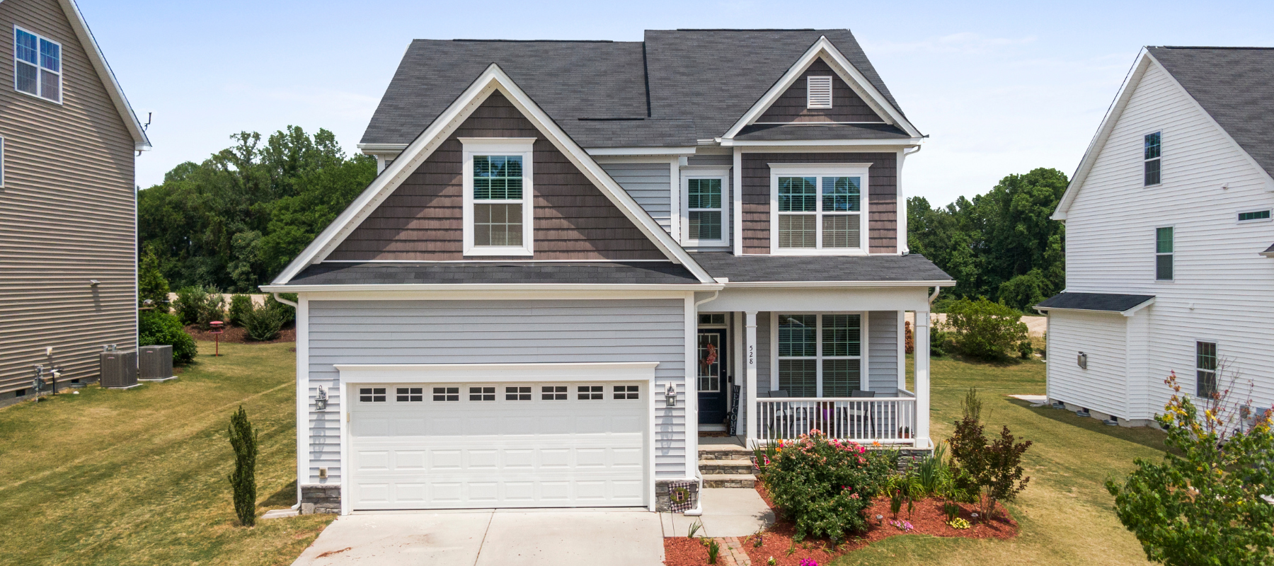 A modern suburban home with a gray and white exterior and a two-car garage