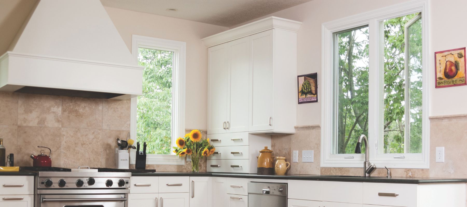 Kitchen with white cabinets and two casement windows overlooking greenery