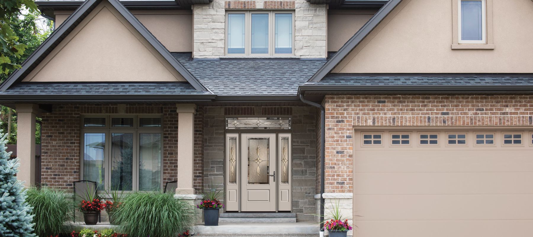 Modern home exterior with a combination of brick, stone, and stucco surrounding a glass-accented front door