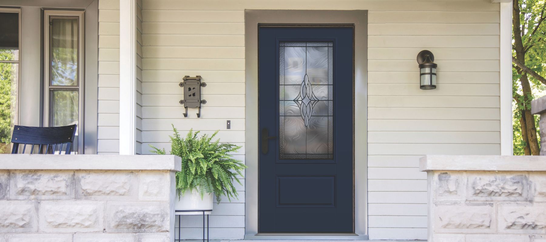 Front entrance with navy blue door and decorative glass, flanked by potted ferns