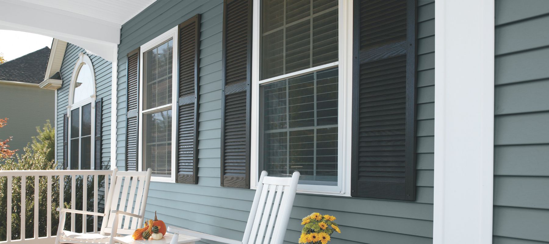 Front porch with teal siding, black shutters, and two white rocking chairs