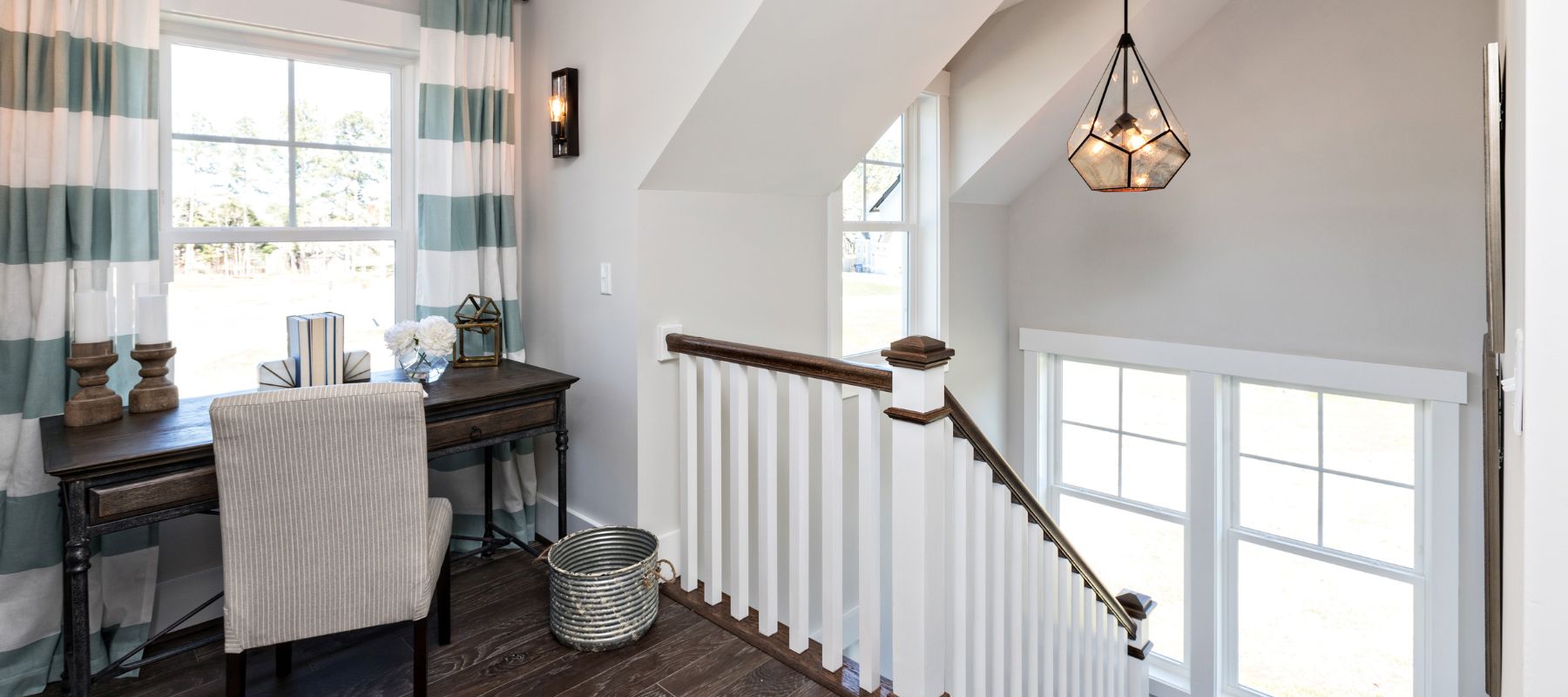 Bright upstairs landing with a desk near striped curtains and multiple white-trimmed windows letting in daylight
